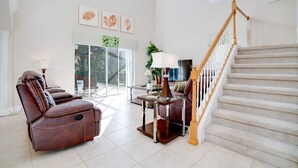A spacious living room with a leather recliner, a glass coffee table, and a staircase. - 2173victoria (Davenport)