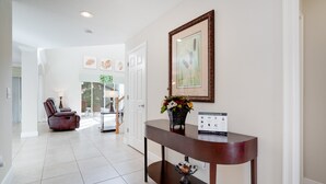 A hallway with a dark wooden console table, a framed artwork, and a potted plant. - 2173victoria (Davenport)