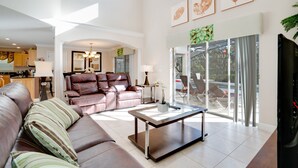 A spacious living room with a leather sofa, a glass coffee table, and a view of the outdoors through large sliding glass doors. - 2173victoria (Davenport)
