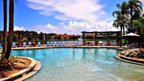 A swimming pool with lounge chairs and palm trees. - 4732tvero (Kissimmee)