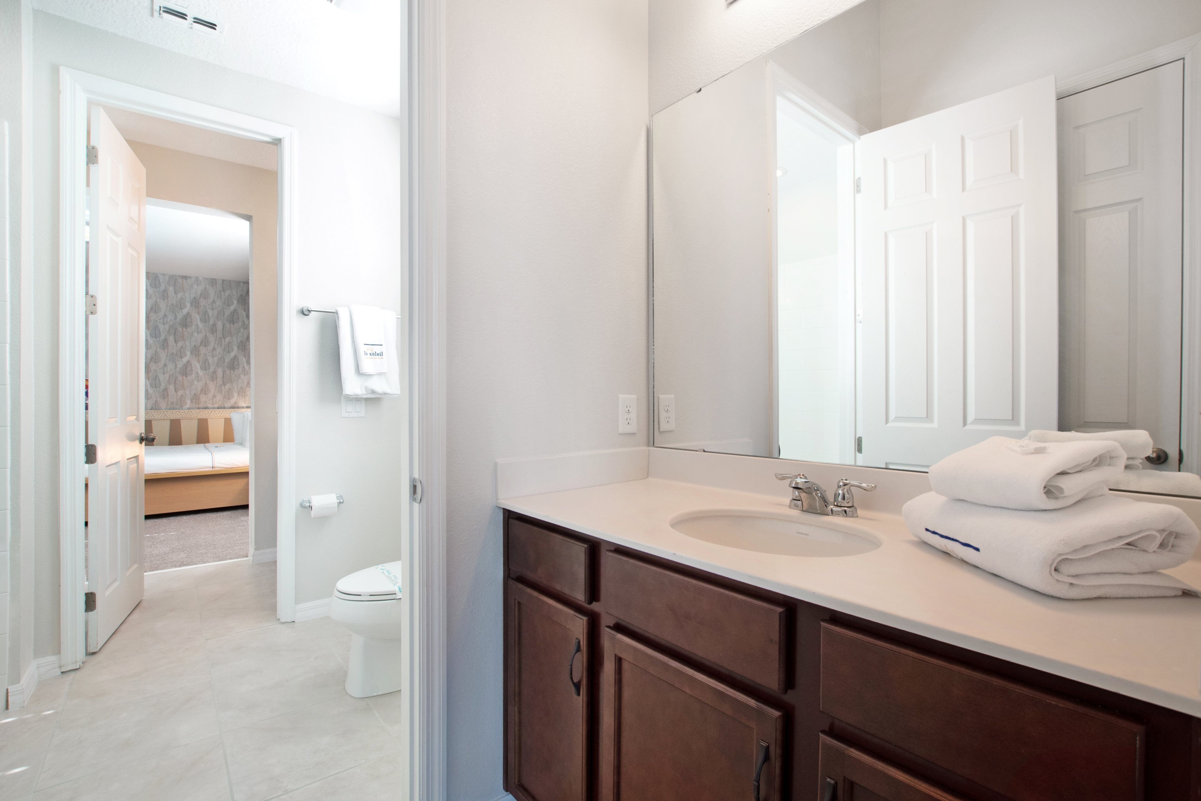 A modern bathroom with a white sink, dark wooden cabinets, and a large mirror.