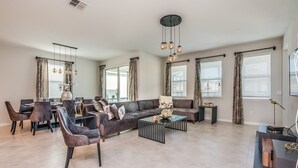 A modern living room with a sofa, chairs, a coffee table, and a dining area.