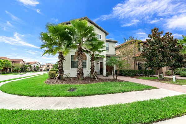 A modern two-story house with a well-maintained lawn, palm trees, and a clear blue sky. - 6bed 5Ba Villa Game Room Pool Spa (Davenport)