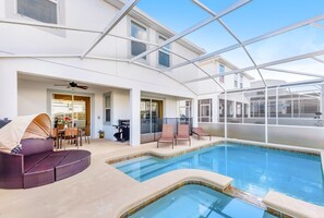 Une piscine intérieure dotée d’un toit en verre, d’un espace salon couvert et d’une terrasse avec des chaises.