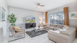 A modern living room with a sofa, armchair, and coffee table. A television is mounted on the wall, and a plant is in the corner. - 1559muligan (Davenport)