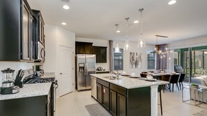 A modern kitchen with a central island, stainless steel appliances, and pendant lighting. - This Dream 6 Bdrm, 5 BA Home (Davenport)