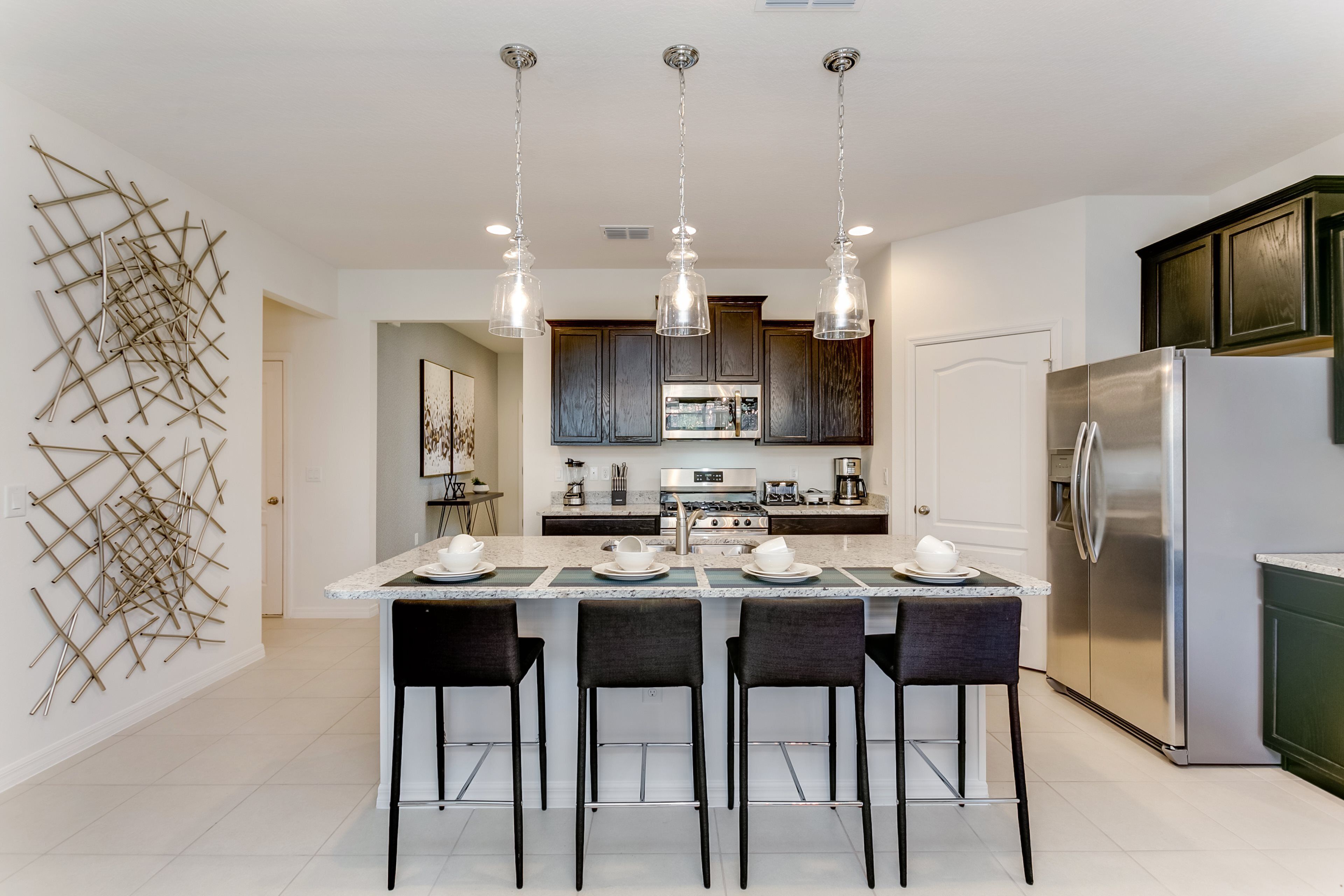 A modern kitchen with a central island, stainless steel appliances, and pendant lighting.