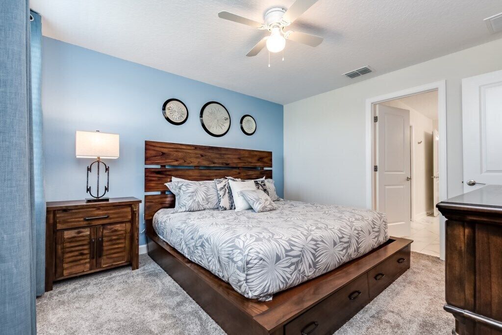 A bedroom with a bed, wooden headboard, bedside tables, and a ceiling fan.