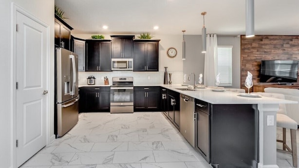 A modern kitchen with dark cabinets, stainless steel appliances, a marble-tiled floor, and a built-in island. - 8 Bed 5 Ba Villa with Games, Pool & Spa (Davenport)