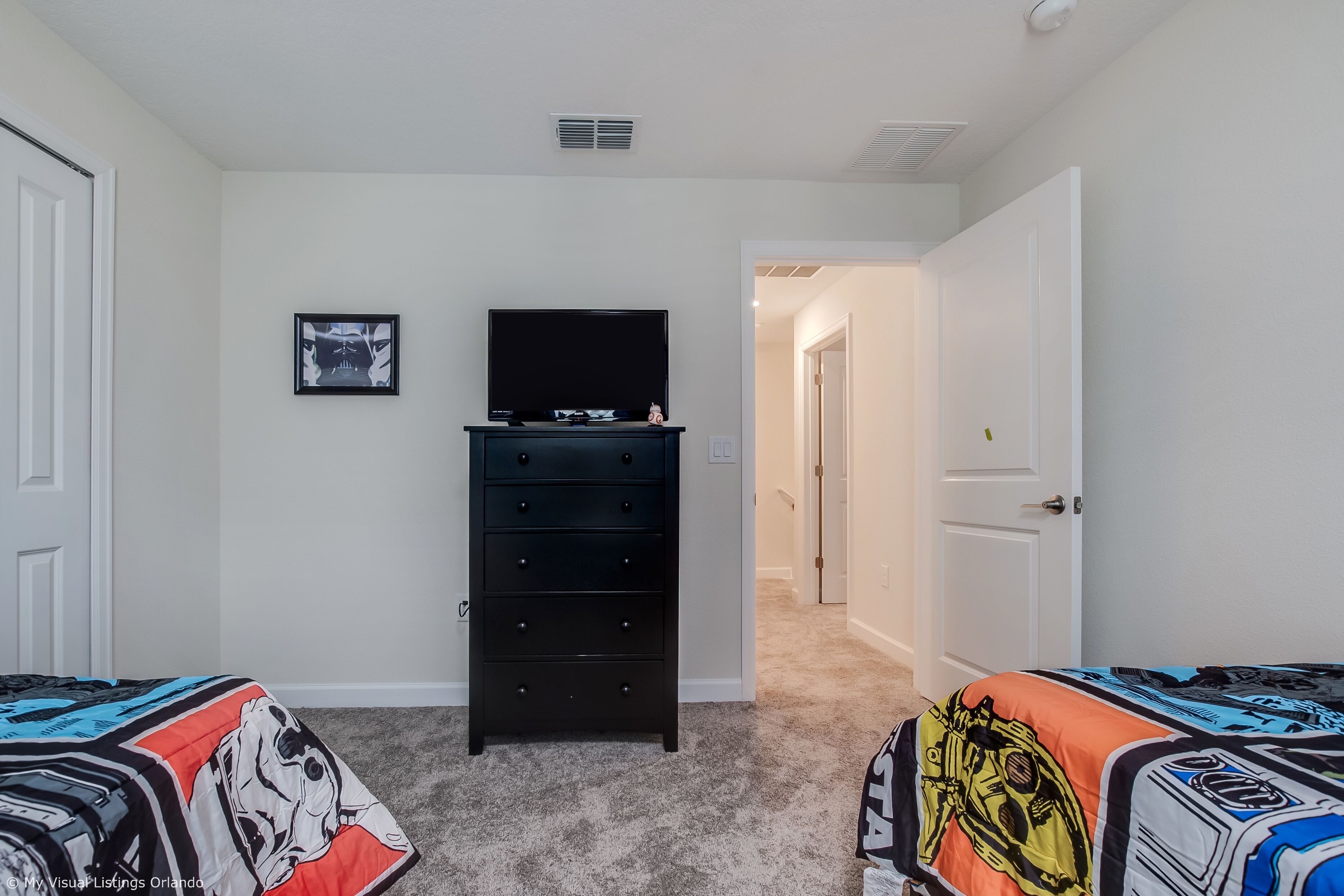 A bedroom with two beds, a dresser, a television, and a framed picture on the wall.
