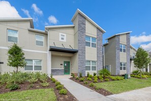 A modern multi-story residential building with a green door, stone accents, and a landscaped front yard. - 780pb Luxury Furnished 5 Bedroom 4 Bathroom (Davenport)