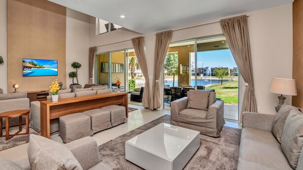 A modern living room with a sofa set, a coffee table, and a TV mounted on the wall. - Modern Magic Village Resort Townhouse 7620 (Kissimmee)