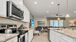 A modern kitchen with white cabinets, a stainless steel range, and a large island with a sink. - 8864bengal (Kissimmee)