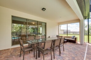 A patio area with a glass-top table and chairs, a cushioned bench, and a view of the outdoors.
