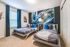 Ett sovrum med två sängar, en stor abstrakt målning, en lampa och ett fönster med gardiner.