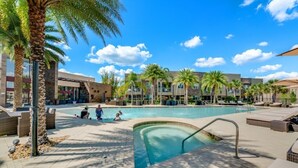A pool area with lounge chairs and palm trees, surrounded by buildings with a modern architectural style. - 7605reclife (Kissimmee)