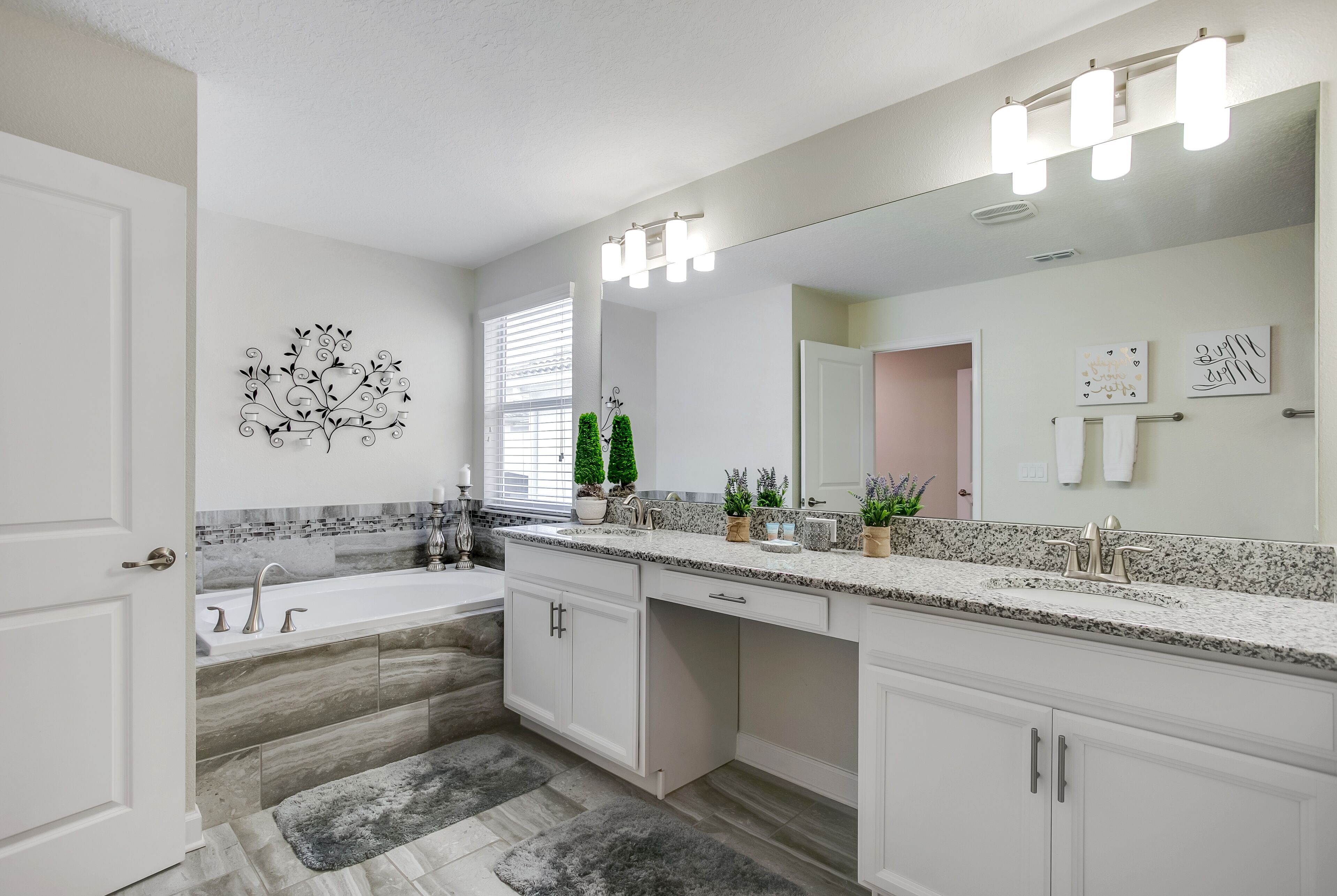 A modern bathroom with a large mirror, vanity, and a bathtub.
