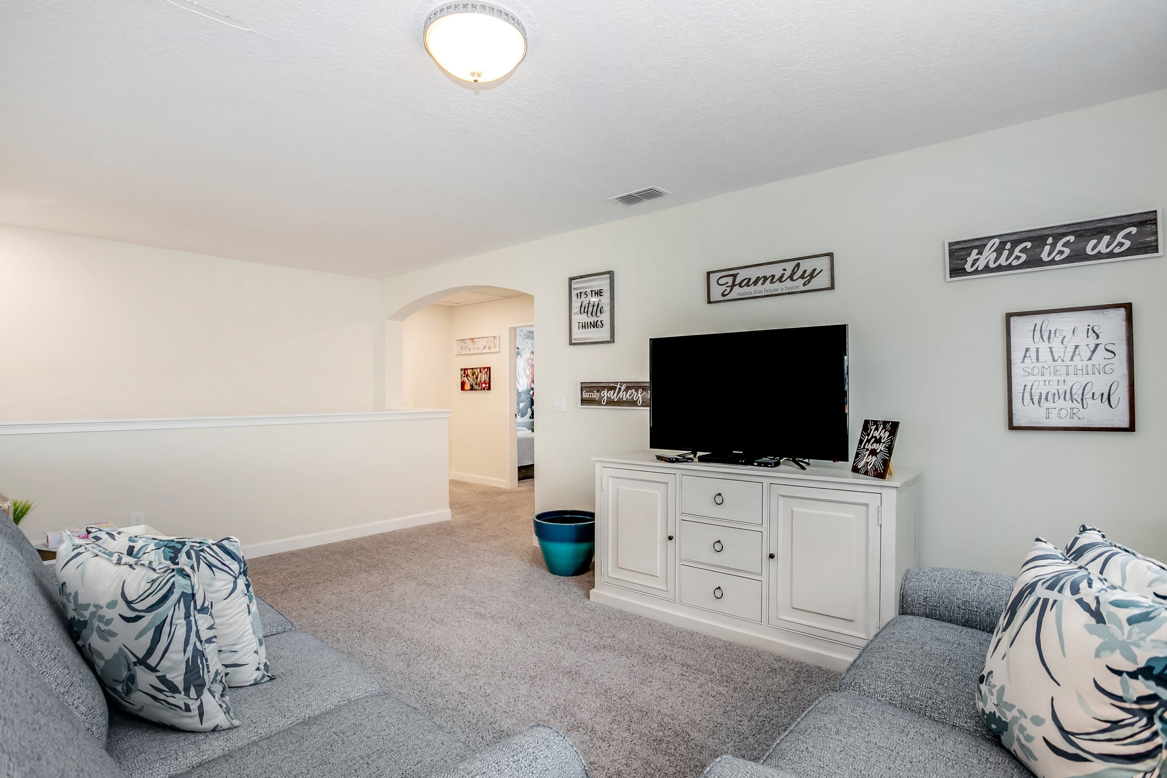 A living room with grey sofas, a flat-screen TV, and a white cabinet.