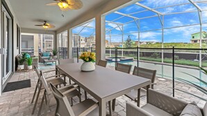 A spacious patio with a dining table, chairs, and a ceiling fan.