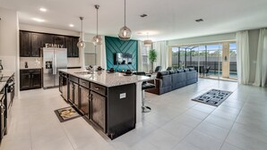 Een moderne keuken met donkere kastjes, een centraal eiland en een zithoek met een bank en stoelen.