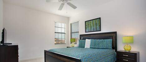A bedroom with a bed, bedside tables, a ceiling fan, and a window with blinds.
