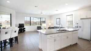 A modern kitchen with white cabinetry, a granite countertop, and a built-in dishwasher. - 2590rose (Davenport)