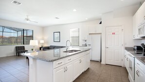 A modern kitchen with white cabinets, a granite countertop, and a built-in microwave. - 2590rose (Davenport)