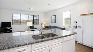 A modern kitchen with granite countertops, white cabinets, a double sink, and a built-in dishwasher. - 2590rose (Davenport)