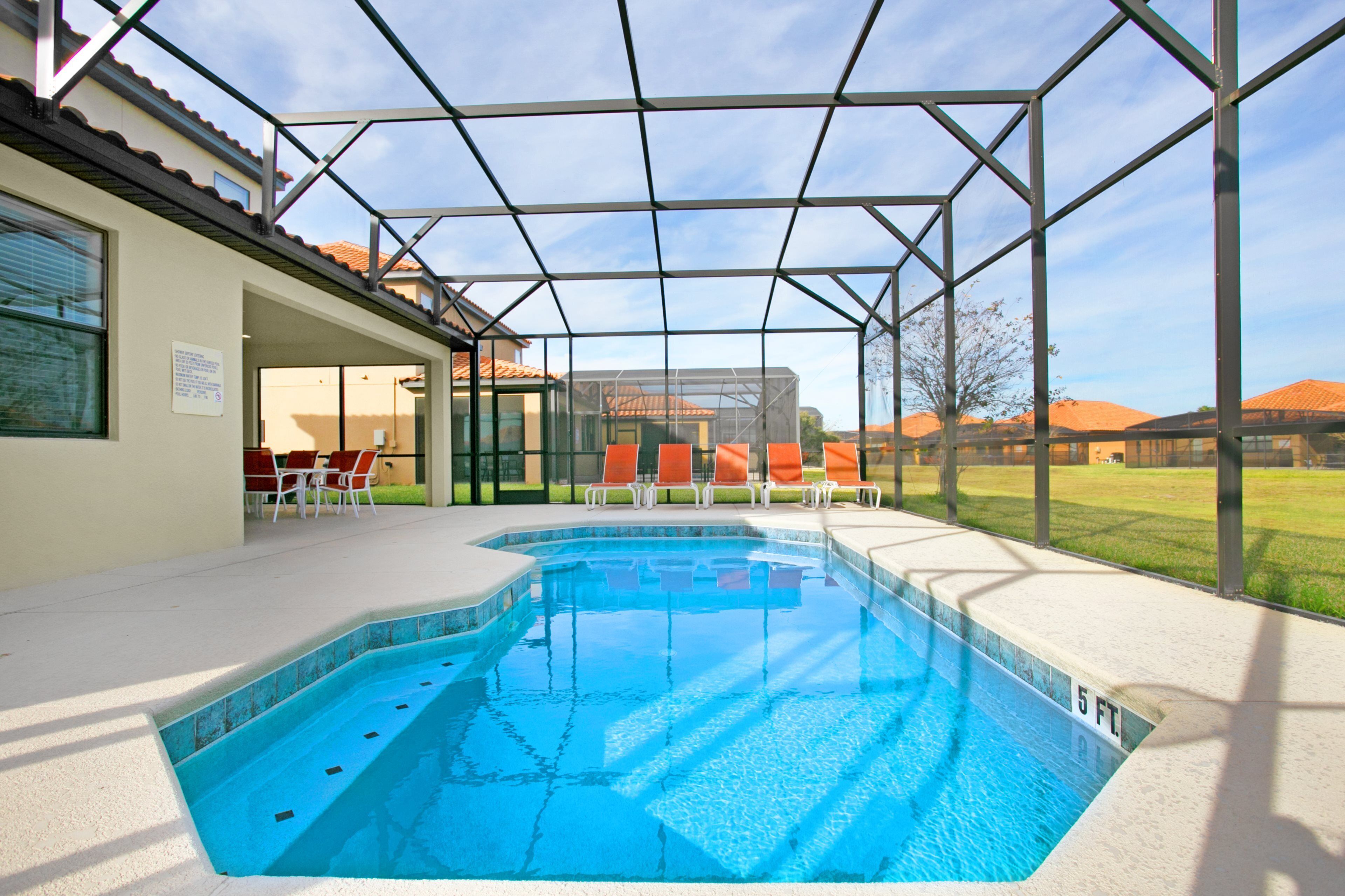 A swimming pool with a glass enclosure, surrounded by lounge chairs and a covered patio area.