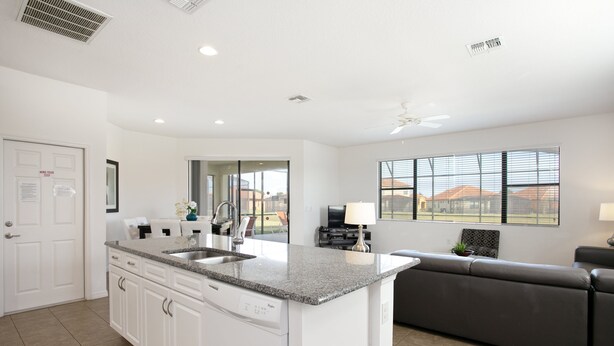A modern kitchen with white cabinetry, a granite countertop, and a built-in dishwasher. - 2590rose (Davenport)