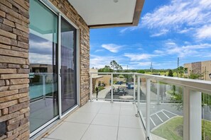 A balcony with a glass door, a clear view of a parking lot, and a building with a brick facade. - 7577brooklin (Kissimmee)