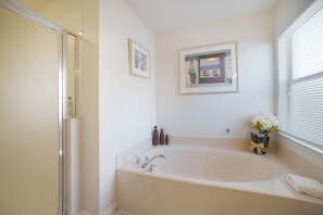 A bathroom with a bathtub, a shower, and a window with blinds. - 204glen (Davenport)