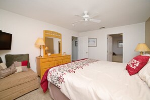 A bedroom with a bed, a dresser, a mirror, a television, and a door leading to another room. - 204glen (Davenport)