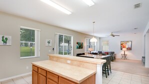 A spacious kitchen with a large island, wooden cabinets, and a dining area with a table and chairs. - 436alderidge (Davenport)