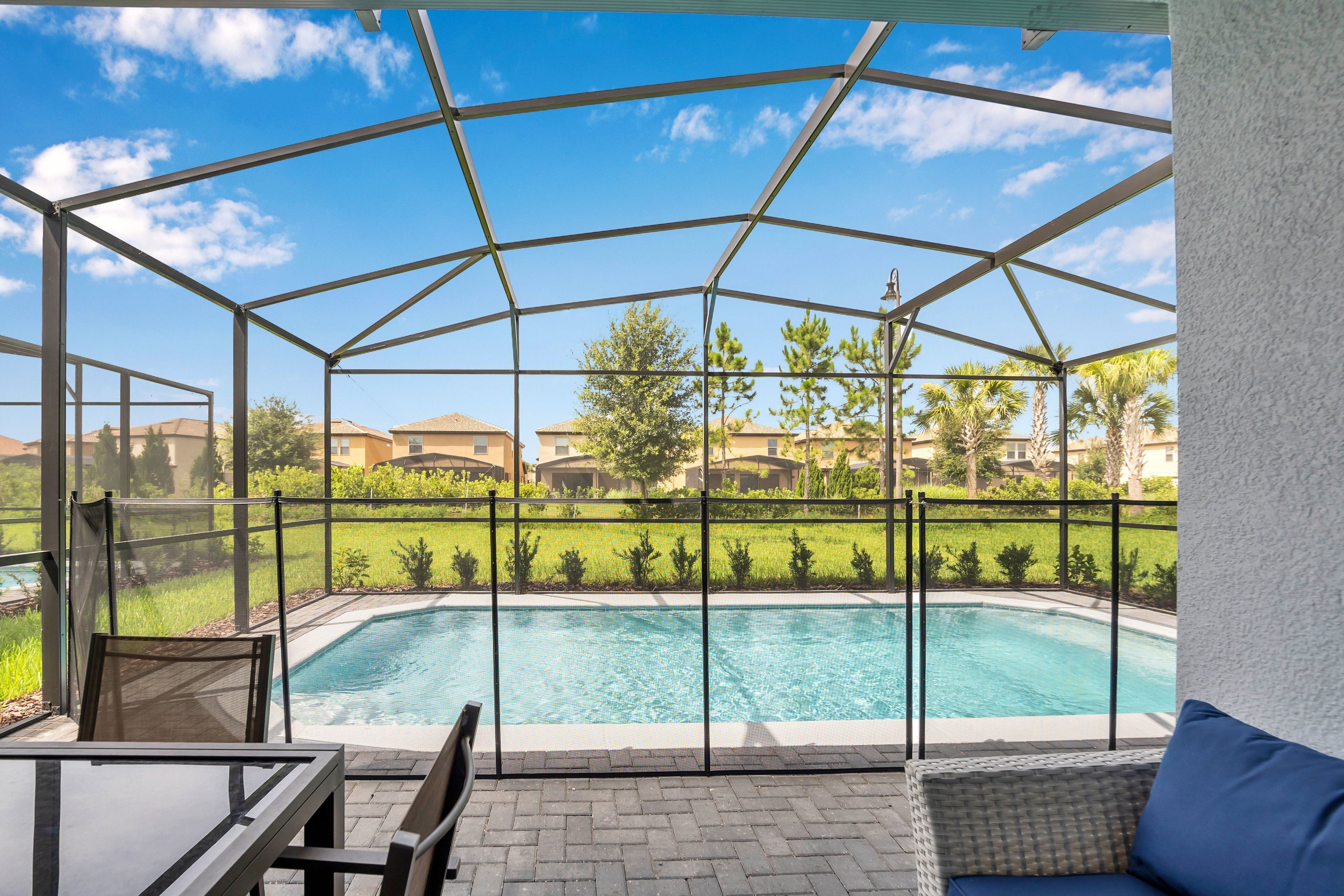 Un espacio exterior techado con piscina, mobiliario y vista a un barrio residencial.