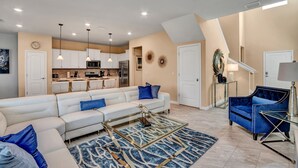A modern living room with a sectional sofa, a glass coffee table, and a blue accent chair. - 5bed 4.5ba Villa Games Pool (Davenport)