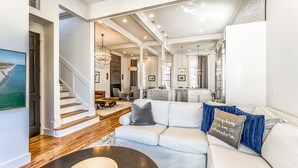A spacious living area with a white sofa, a coffee table, and a staircase leading to another level. - Sandpiper Cottage - Four Bedroom Close to Pool & Beach (Rosemary Beach)