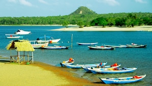 A beach with several boats docked near the shore, a small hut, and a hill in the background. - Curuá House (Alter do Chão)