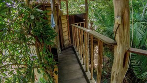 A wooden deck with a curved roof, surrounded by lush greenery. - Curuá House (Alter do Chão)