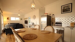 A modern kitchen with a wooden dining table, chairs, and a refrigerator. - Bridgecroft Villa (Richmond)