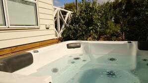 A hot tub with a wooden deck and a white railing. - Bridgecroft Villa (Richmond)