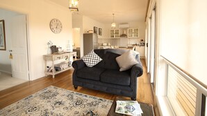A living room with a dark sofa, a patterned rug, and a clock on the wall. - Bridgecroft Villa (Richmond)