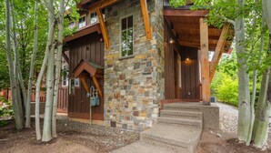 A rustic cabin with a stone and wood exterior, surrounded by trees.