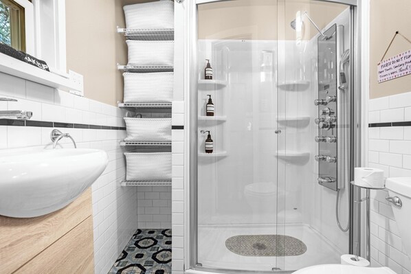 A modern bathroom with a white sink, a glass-enclosed shower, and a patterned floor.