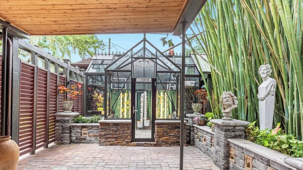 A greenhouse with a sign reading "L'ORANGERIE," surrounded by bamboo plants and stone walls. - Lake House Pets allowed (Orlando)