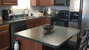 A kitchen with wooden cabinets, a stainless steel refrigerator, a microwave, and a coffee maker.