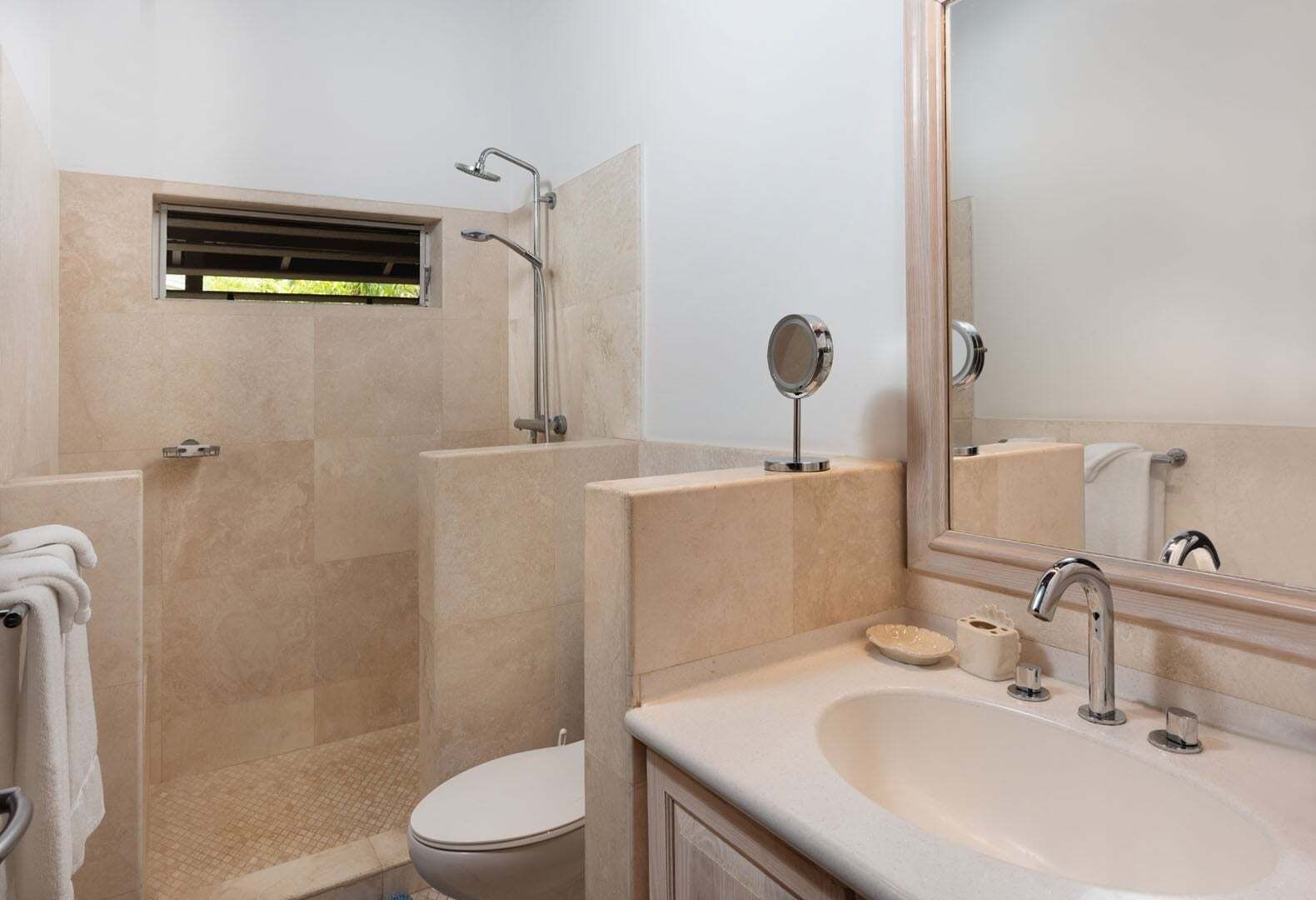A bathroom with a shower, toilet, sink, and a mirror.