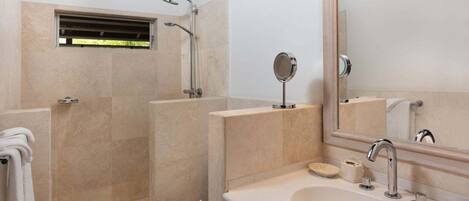 A bathroom with a shower, toilet, sink, and a mirror.