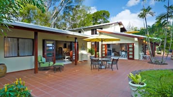 A modern house with a patio area featuring outdoor furniture and a dining table.