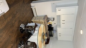 A compact kitchen with a dining area, white cabinetry, and a wooden floor. - 1 bedroom apt.Minutes to Encore Casino and Boston. (Revere)